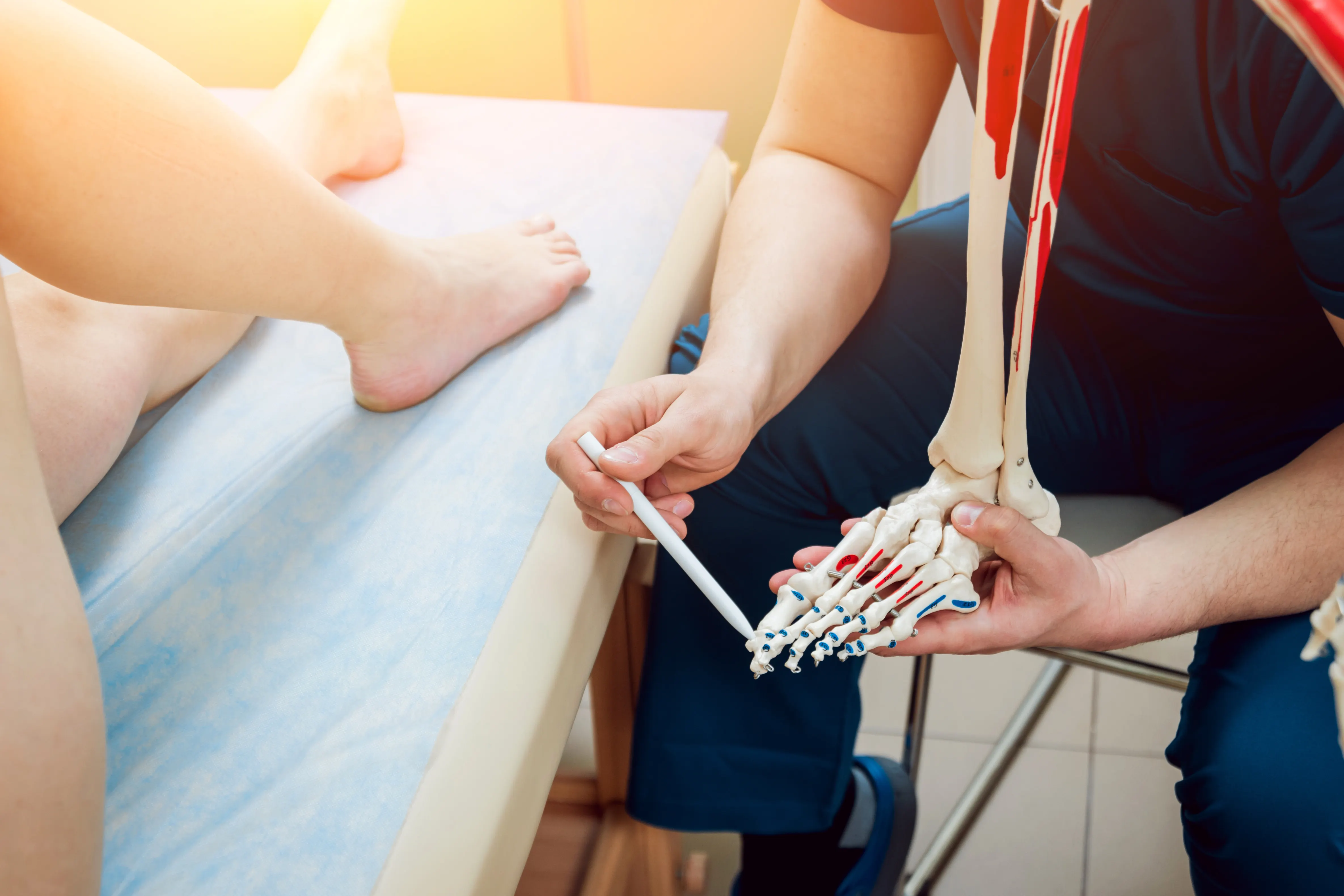 A podiatrist using a foot model to explain treatment to a patient